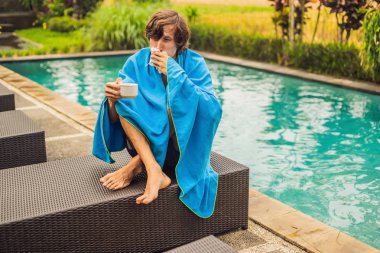 Havuzu oturan ve peçete ile burun üfleme ve sıcak çay içme hasta adamı 