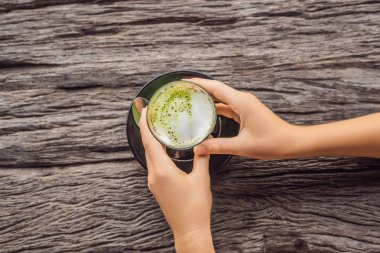 matcha latte ahşap masa üzerinde bardak tutan eller
