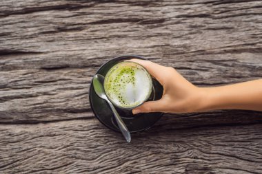 matcha latte ahşap masa üzerinde bardak tutan el