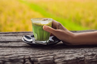 matcha latte ahşap masa üzerinde bardak tutan el