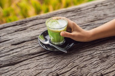 matcha latte ahşap masa üzerinde bardak tutan el