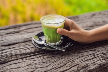 matcha latte ahşap masa üzerinde bardak tutan el