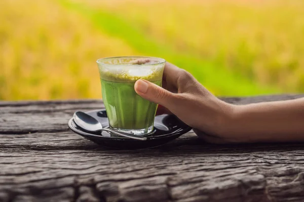 Γυναικείο Χέρι Που Κρατά Φλυτζάνι Του Latte Matcha Στο Ξύλινο — Φωτογραφία Αρχείου