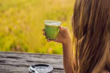 Genç kadın pirinç terasları Bali, Endonezya yakınındaki kafe verandada Matcha latte içmek