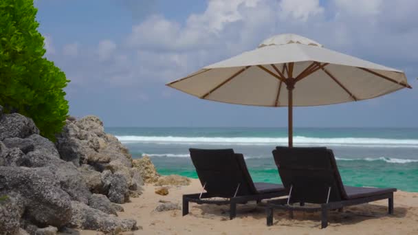 荒波背景にビーチチェアと大きな日傘 — ストック動画