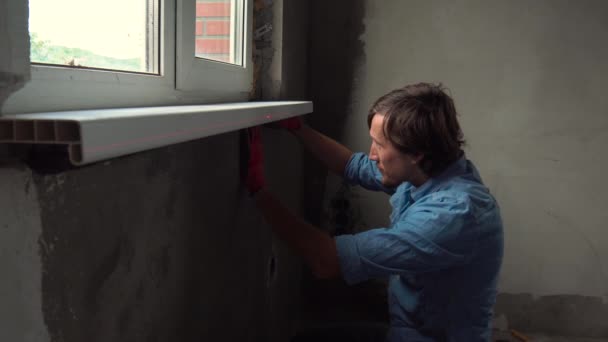 室内の窓枠をインストールする手袋の若い男 — ストック動画