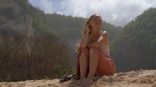 Jeune Femme Assise Sur Sable Avec Des Rochers Arrière Plan — Video