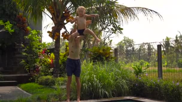 お父さんの Superslowmotion ショットは、熱帯地方でプールに彼の息子をスローします。 — ストック動画
