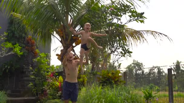 お父さんの Superslowmotion ショットは、熱帯地方でプールに彼の息子をスローします。 — ストック動画