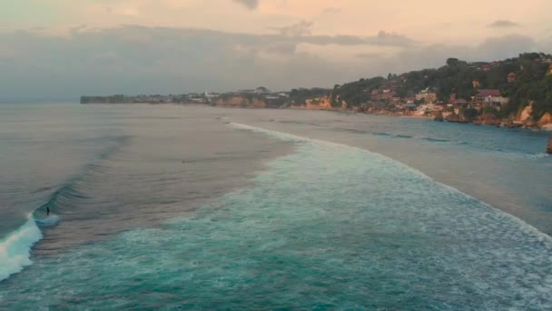 Aerial slowmotion skott av en spot surfing på en tropisk ö i solnedgången — Stockvideo