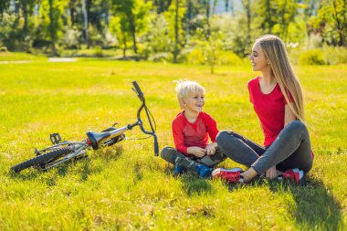 Anne ve oğlu çimenlerin üzerinde bisiklete binmek sonra dinlenme