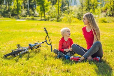 Anne ve oğlu çimenlerin üzerinde bisiklete binmek sonra dinlenme