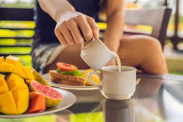 桌上咖啡杯里的女人倒牛奶 — 图库照片