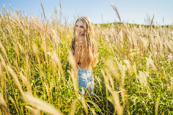 Mujer hermosa joven en el paisaje de otoño con flores secas, espigas de trigo. Moda otoño, invierno. Otoño soleado, foto de moda — Foto de Stock