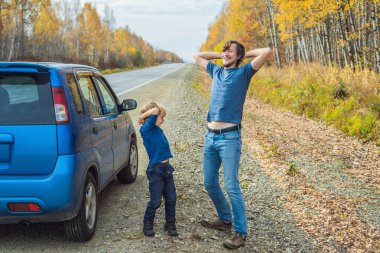 Baba ve oğul aile gezisi sırasında yol kenarında eğleniyor.