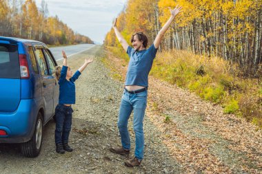 Baba ve oğul aile gezisi sırasında yol kenarında eğleniyor.
