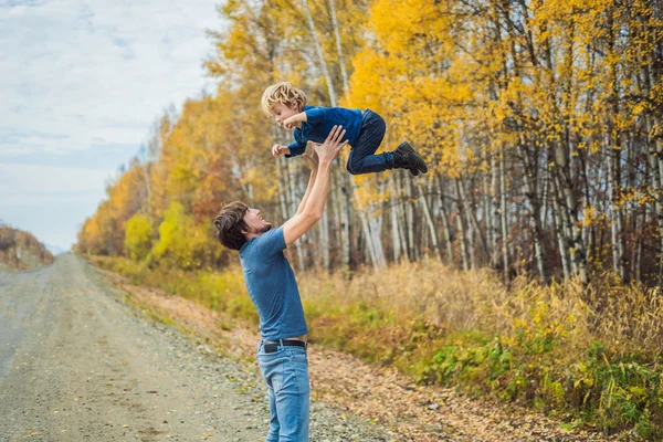 Papa speelt met zijn zoon op de achtergrond van de herfst bos — Stockfoto