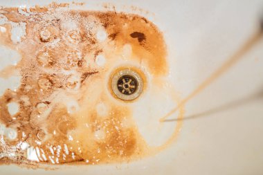 Beyaz bir lavabo içine musluk düşen kirli kahverengi akan su. Çevre kirliliği kavramı