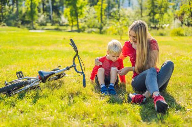 Çocuk Bisiklet düştü, annesi bir sıva dizinde yapıştırır.
