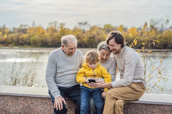 El niño muestra la foto en el teléfono a sus abuelos — Foto de Stock