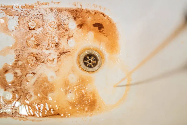 Dirty brown running water falling into a white sink from tap. Environmental pollution concept — Stock Photo, Image