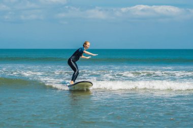 Genç kadın mavi acemi sörf küçük deniz dalga tatil tropikal sörf öğrenme.