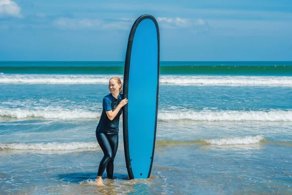 Young woman in swimsuit with surf for beginner ready to surf.