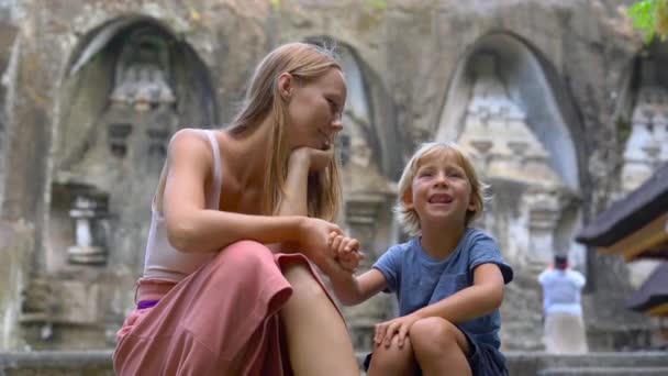 母とグヌン カウィ スバトゥ寺院バリ島に座って息子のスローモーション撮影 — ストック動画