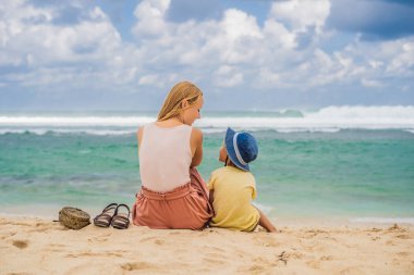 Anne ve oğlu kumsalda dinlenmek ve zevk ile turkuaz su, Bali Adası, Endonezya Melasti Beach amazing görüntülemek.