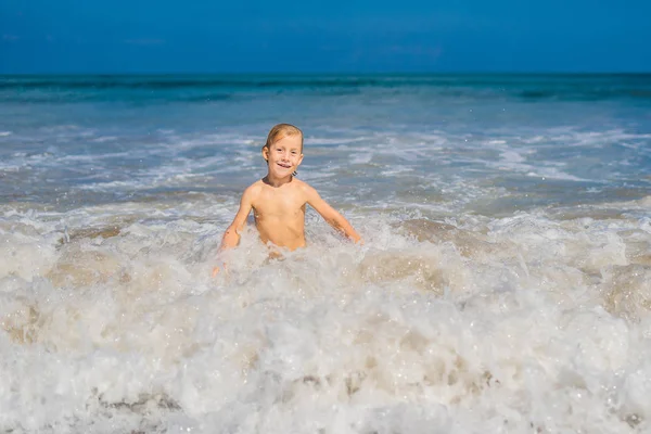 エキゾチックな海岸線に打ち寄せる波で遊ぶ少年 — ストック写真