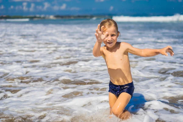 エキゾチックな海岸線に打ち寄せる波で遊ぶ少年 — ストック写真