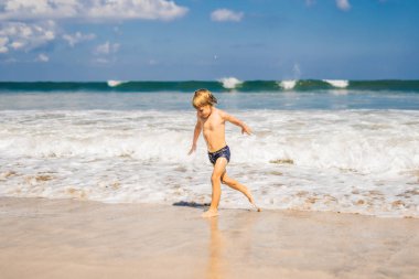 Okyanus su tropik sahilde oynarken küçük çocuk.