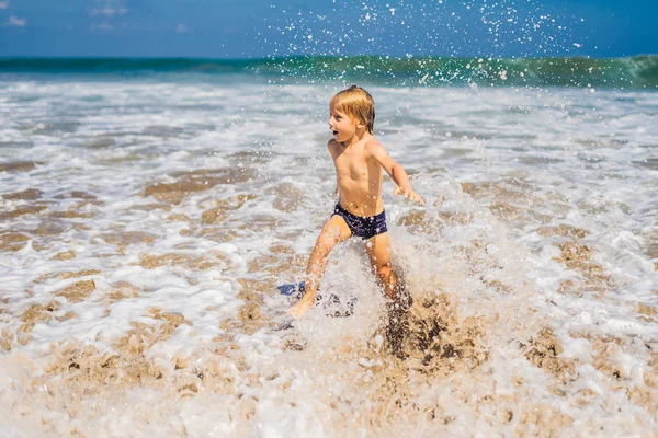 Okyanus su tropik sahilde oynarken küçük çocuk.