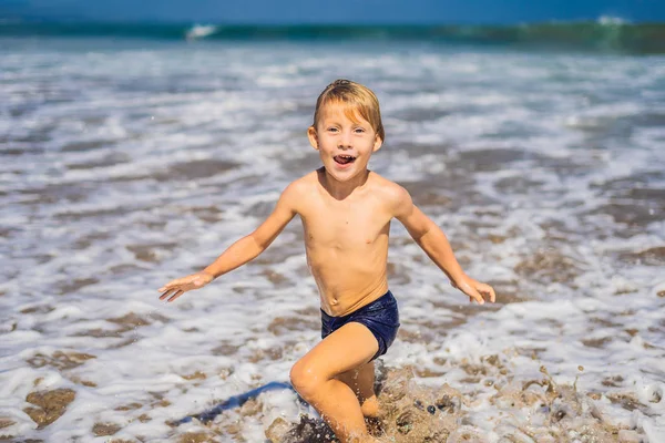 熱帯のビーチで海の水で遊ぶ少年 — ストック写真