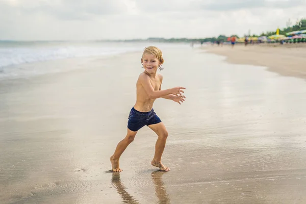 海の水の砂浜で遊ぶ少年 — ストック写真