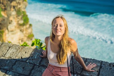 Genç kadının taş duvar Pura Luhur Uluwatu Tapınağı, Bali, Endonezya, güneş ışığı.