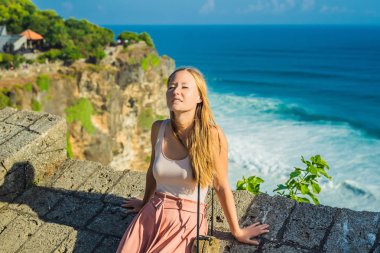 Genç kadının taş duvar Pura Luhur Uluwatu Tapınağı, Bali, Endonezya, güneş ışığı.