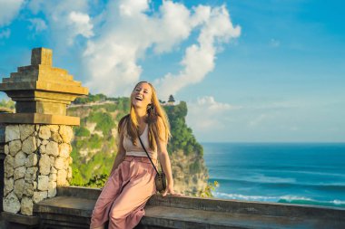 Pura Luhur Uluwatu Tapınağı, Bali, Endonezya taş duvarda oturan genç kadın gezgin. 