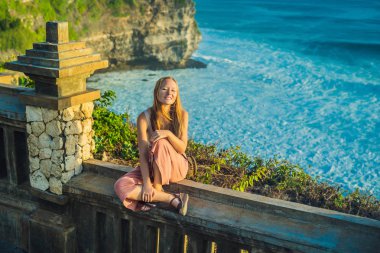 Pura Luhur Uluwatu Tapınağı, Bali, Endonezya taş duvarda oturan genç kadın gezgin. 