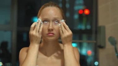 Genç kadın duşta makyaj yüzünden kaldırır.