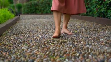 tropikal bir parkta reflexological bir yolda yürüyen genç bir kadın görüntüsünü Slowmotion