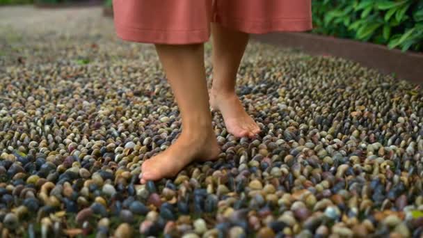 Toma en cámara lenta de una joven mujer caminando por un sendero reflexológico en un parque tropical — Vídeos de Stock