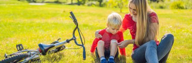 Çocuk Bisiklet düştü, annesi bir sıva dizinde afiş, uzun biçimde yapıştırır.