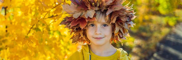 Ritratto di bambino sorridente con ghirlanda di foglie sullo sfondo del soleggiato parco autunnale BANNER, FORMATO LUNGO — Foto Stock