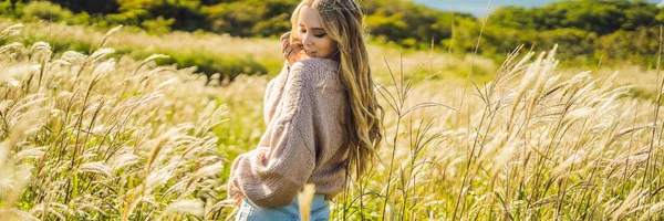 Mooie jongedame in herfst landschap met droge bloemen, tarwe pieken. Mode najaar, winter. Zonnige herfst, gezellige herfst trui. mode foto Banner, lange notatie — Stockfoto