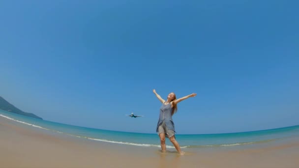 PHUKET, THAILAND - OCT. 12: Slowmotion shot of a young woman on a beach with a airplane flying over her — Vídeo de Stock