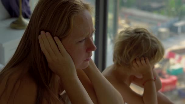 一名年轻女子和她的儿子坐在床上, 受到外面建筑工地产生的噪音的影响 — 图库视频影像