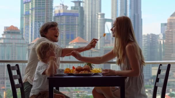 家族は 市内中心部の高層ビルを見渡すバルコニーで朝食をとる — ストック動画