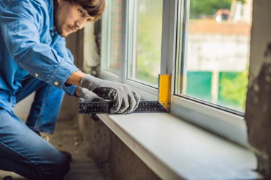 Evde pencere yüklemesi mavi tişörtlü adam.