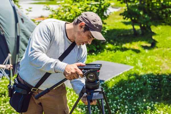 プロのカメラマンが撮影前に、カメラと三脚を準備します。 — ストック写真